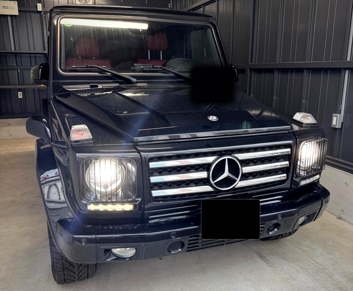 Schwarze Mercedes-Benz G-Klasse mit eingeschaltetem Licht, Frontansicht